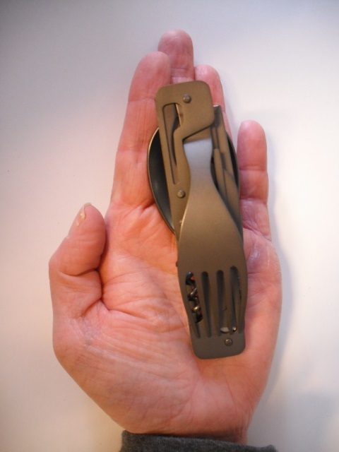 Eine Hand hält ein kleines Edelstahl Faltbesteck mit mehreren Funktionen.